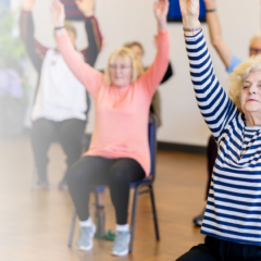 Older adults participating in a seated exercise class with arms raised